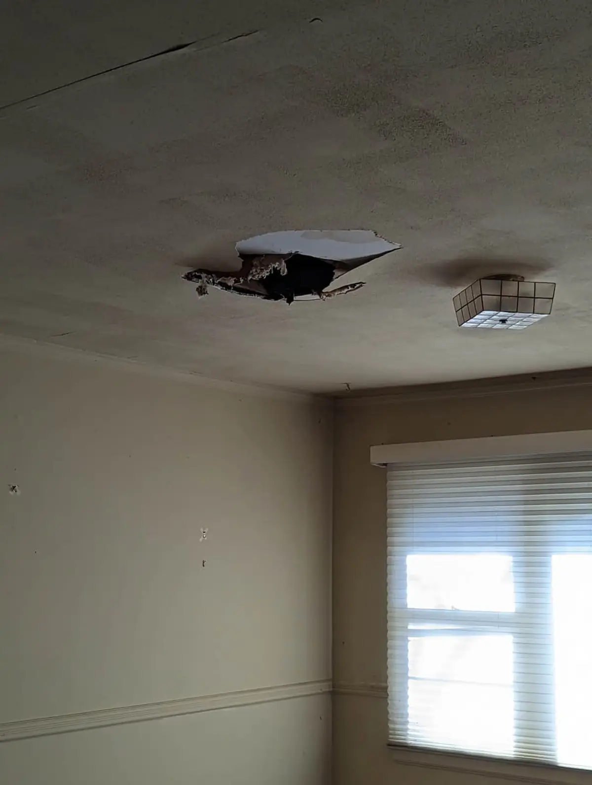 Selling a house for a job relocation in Westbury: bedroom ceiling with a large hole in the drywall