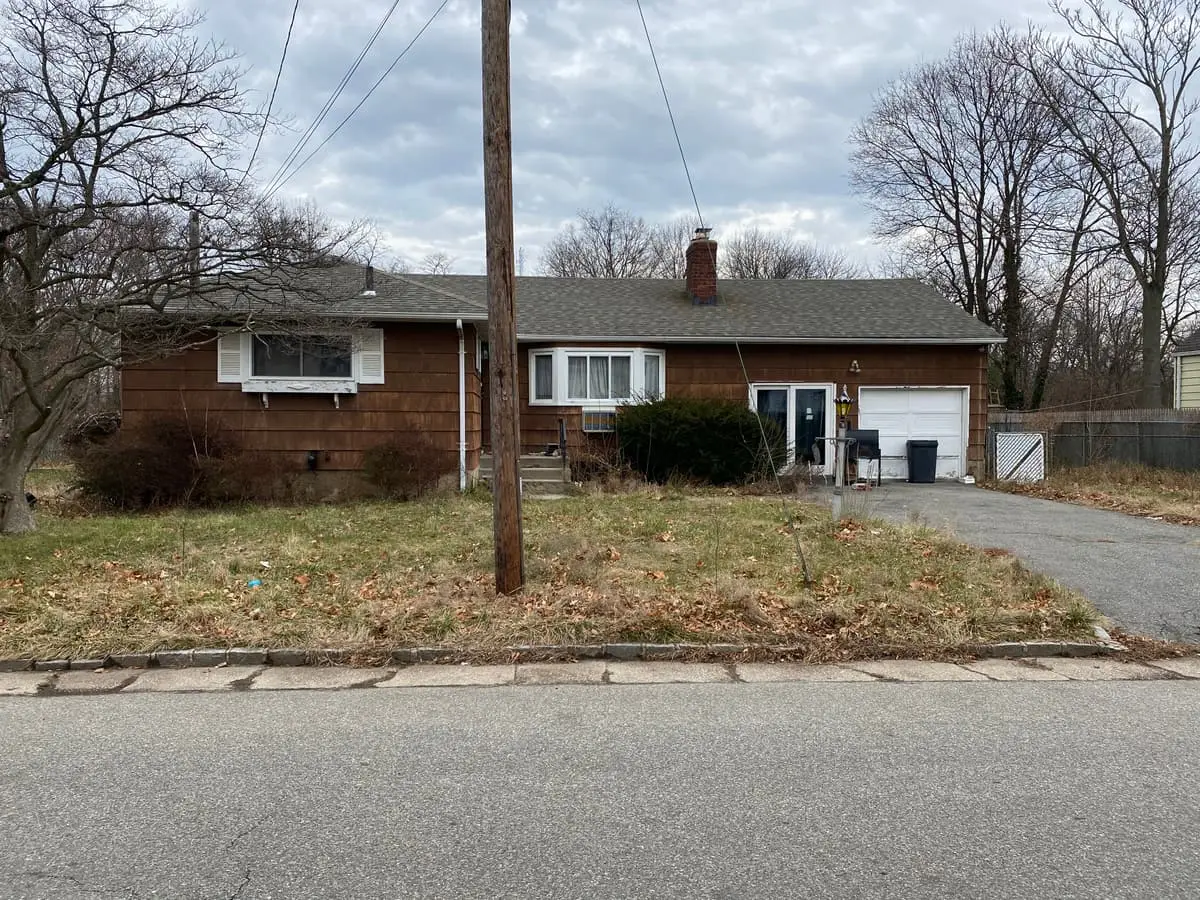 Selling a multi-family house in Westbury: brown shingled ranch with an unkempt front lawn