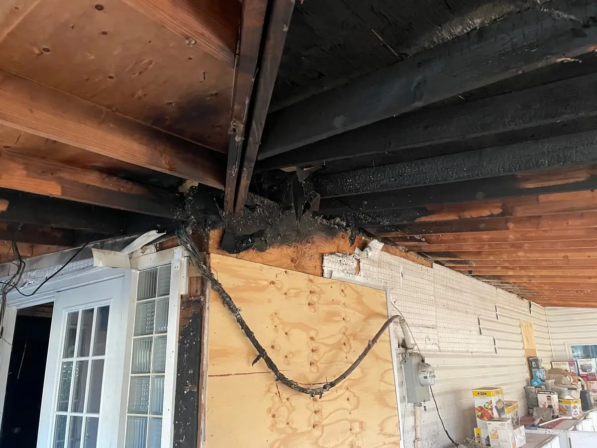 Selling a house with foundation problems in Westbury: charred ceiling joists above a boarded window