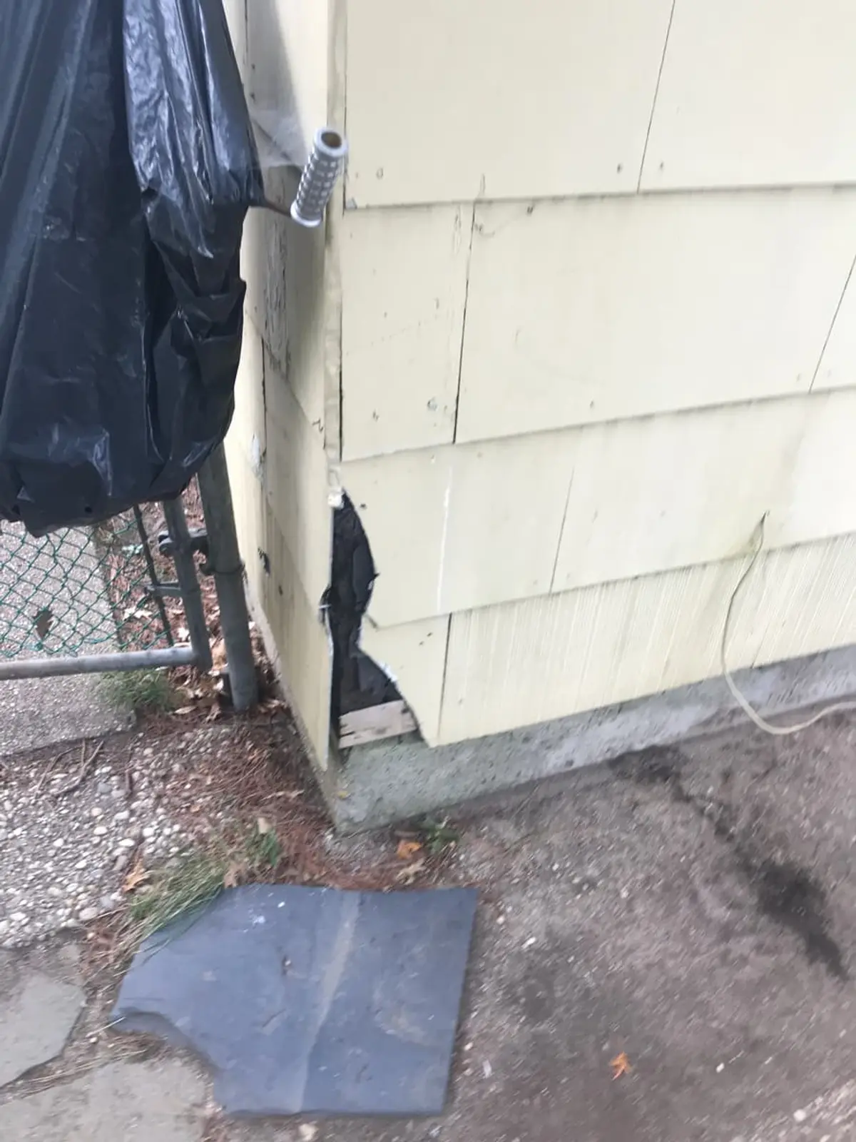 Selling a house as-is in Westbury: cracked siding panel broken open at a corner