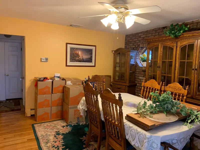 Dining room with an oak hutch and stacked moving boxes, Westbury, NY