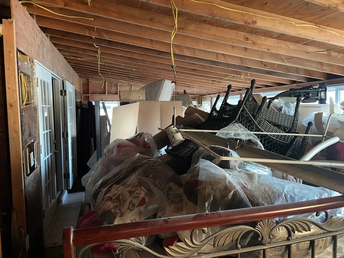 Selling a hoarder house in Westbury: furniture and bagged belongings piled under bare joists
