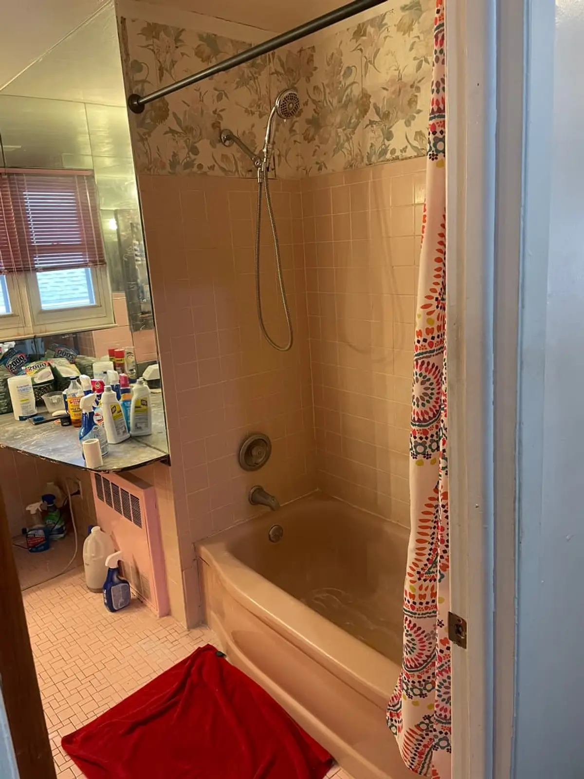 Selling a parent’s house after a move to care in Westbury: pink tub and tile with cleaning supplies on the counter