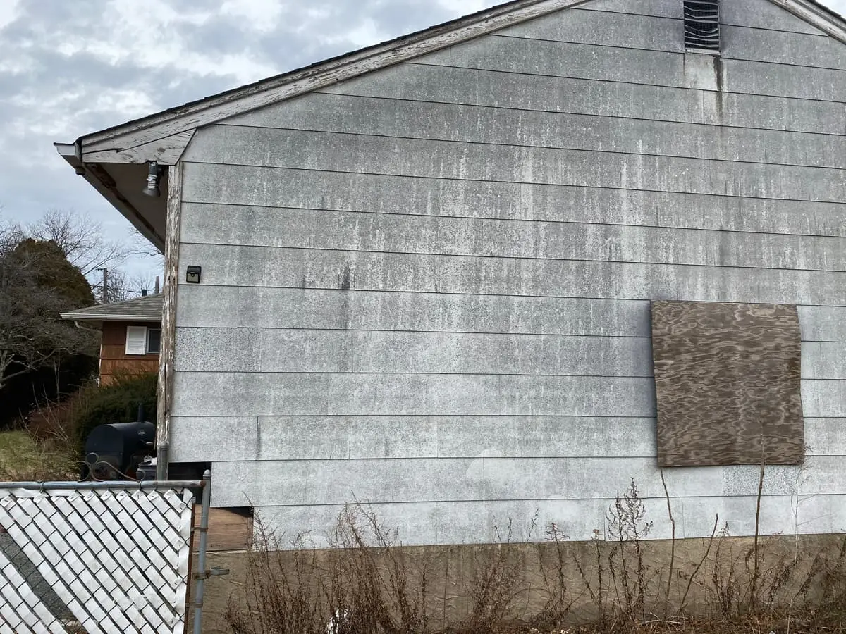 Trying to stop a foreclosure in Westbury: weathered siding with a plywood boarded window