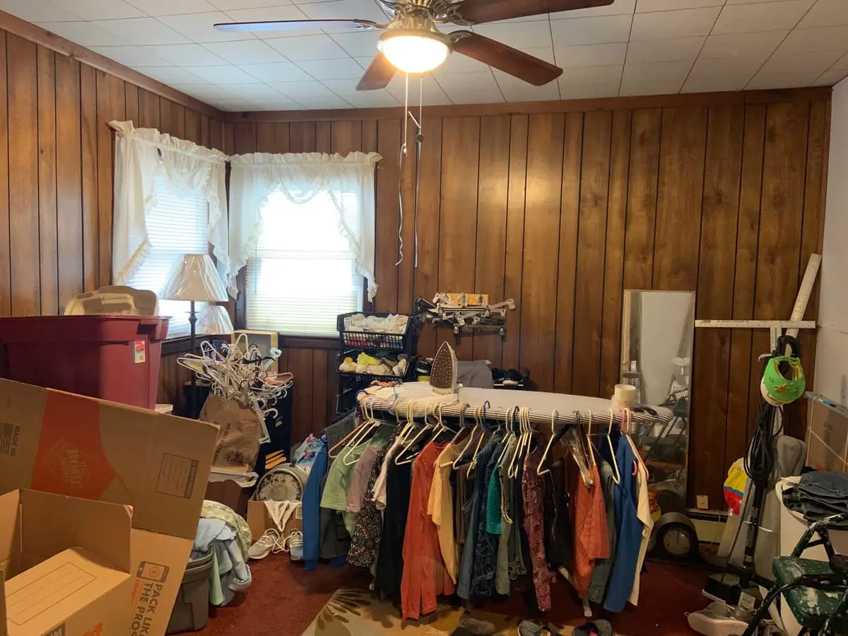 Selling a house during a divorce in Westbury: wood paneled room crowded with clothes racks and boxes